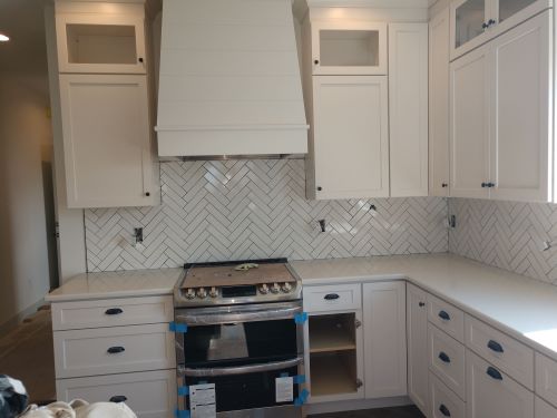 Kitchen with white cabinets and white tile backsplash and accents. 